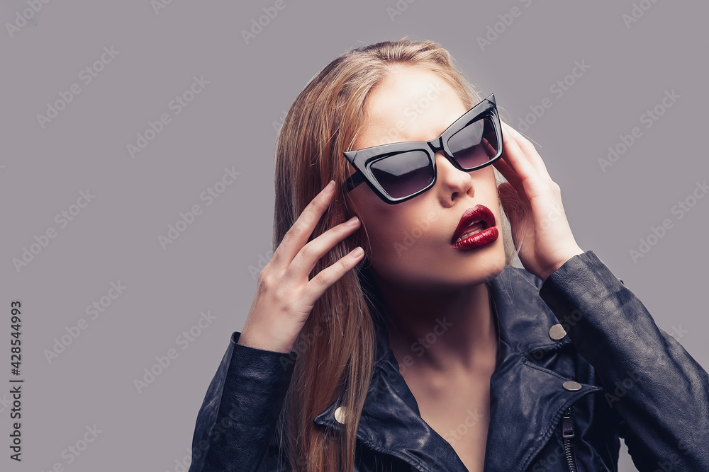 Fashion portrait of young elegant woman in black leather jacket, sunglasses Fashion portrait of young elegant woman in black leather jacket, sunglasses