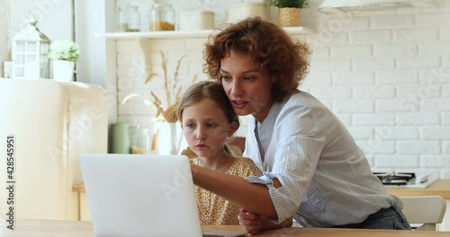 Mother helps to daughter with schoolwork using laptop, homeschooling due quarantine, internet education app usage, clap hands celebrate successful task accomplishment. Teach kid, study online concept