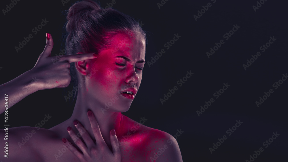 Woman in artistic makeup on dark background, holding finger to the temple, simulating a shot
