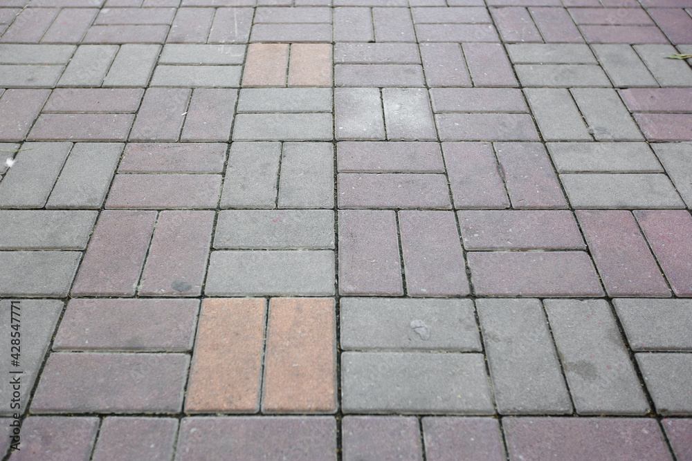 Perspective view of brick block stone pavement pattern surface in the city. People walking street footpath. Dirty pavement.