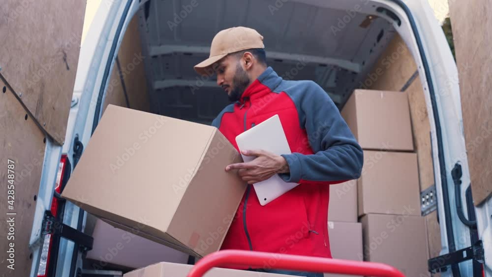 Young Indian man using a tablet to check delivery order. Loading truck with cardboard boxes. High quality 4k footage Young Indian man using a tablet to check delivery order. Loading truck with cardboard boxes. High quality 4k footage