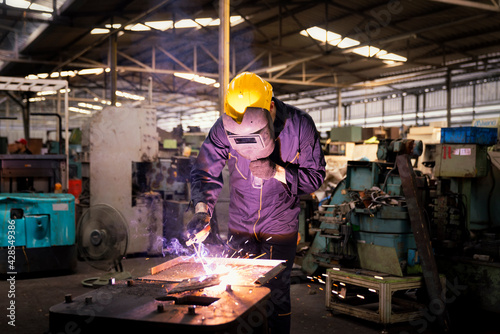 Factory technicians are welding young. Metal welding steel works using electric arc welding machine to weld steel at factory.
