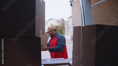 Young courier unloading parcels from the truck. High quality 4k footage