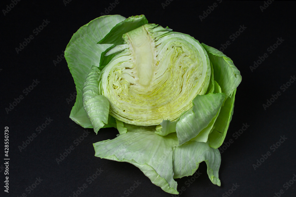 Fototapeta premium Cabbage on a dark background. Half of cabbage on a black background. Young fresh cabbage. Healthy diet