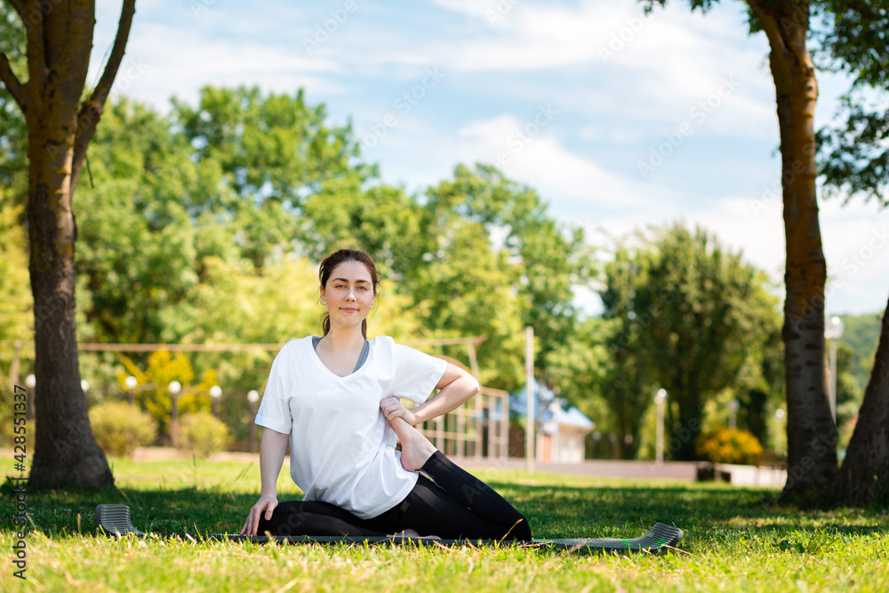 Yoga. A young woman in sports clothes, doing an exercise in the Park on the grass. Copy space. The concept of sport for a healthy lifestyle Yoga. A young woman in sports clothes, doing an exercise in the Park on the grass. Copy space. The concept of sport for a healthy lifestyle
