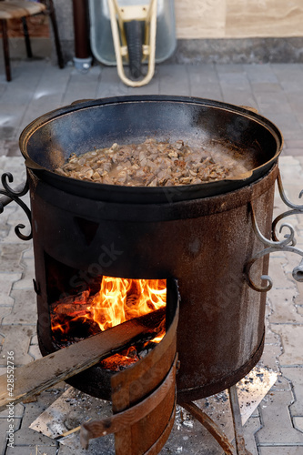 A huge amount of lamb pilaf in the process of cooking in a cauldron over an open fire