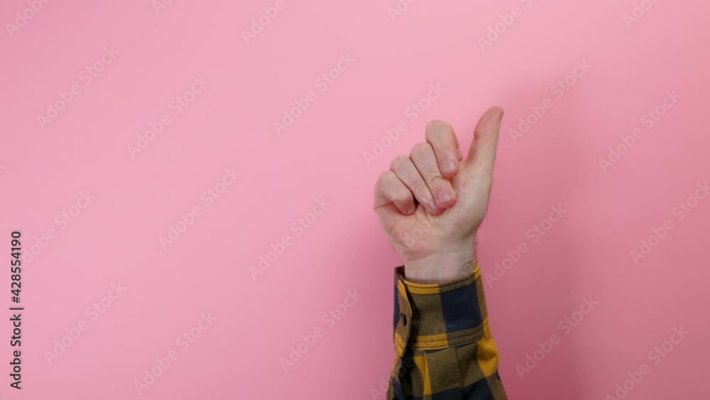 A male's hand appears from below and gives a thumb up. Pink background. Concept of positive communication and gestures. A male's hand appears from below and gives a thumb up. Pink background. Concept of positive communication and gestures.