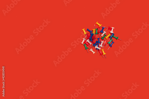 heap of pushpins. paperclip, staple, paperfastener on red background photo