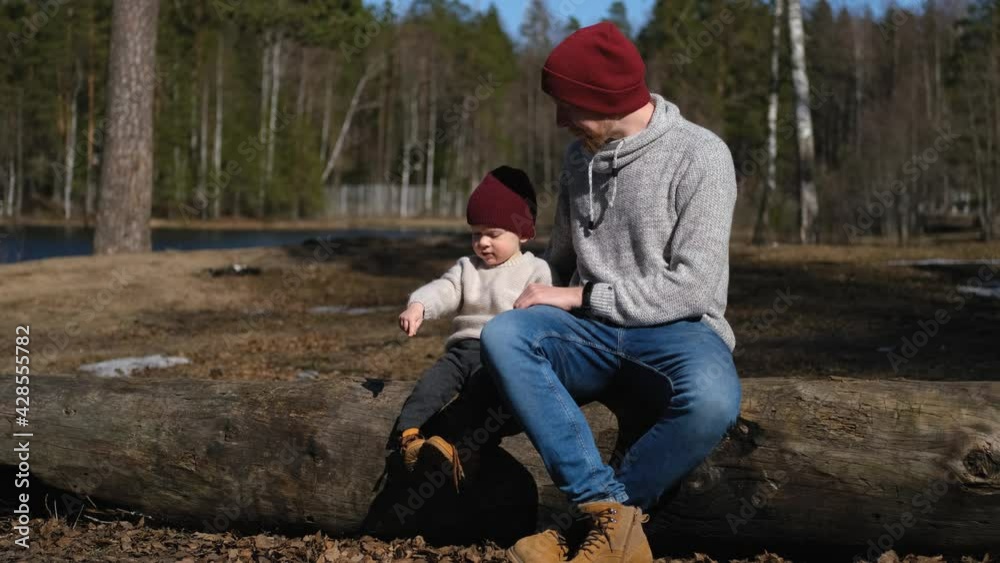 father and little son communicate while sitting on a log in the forest father and little son communicate while sitting on a log in the forest