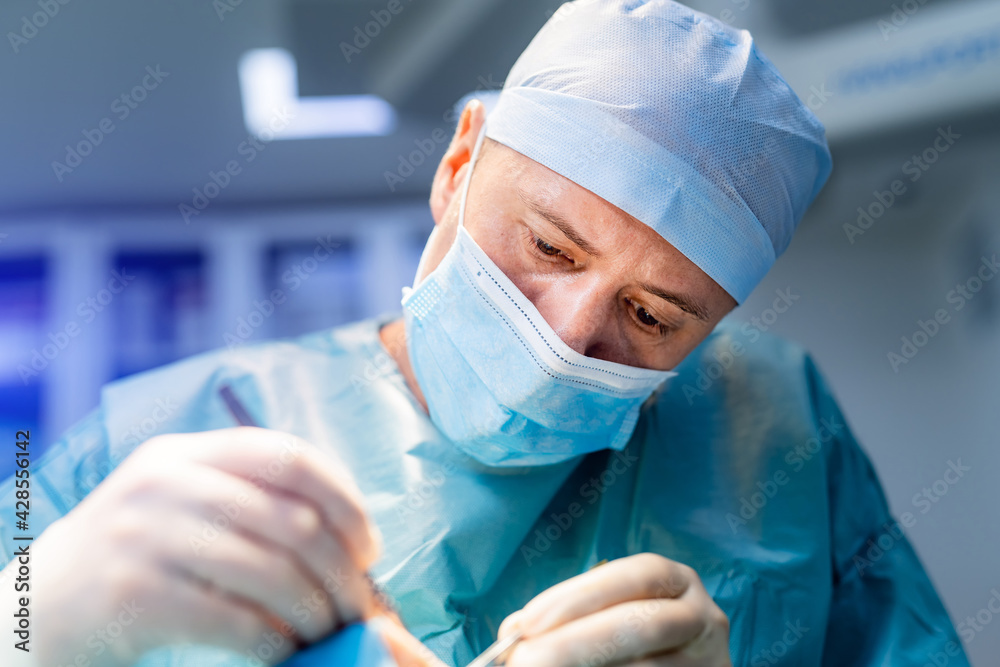 Thoughtful doctor doing operation. Adult man in blue uniform helping people in hospital. Thoughtful doctor doing operation. Adult man in blue uniform helping people in hospital.