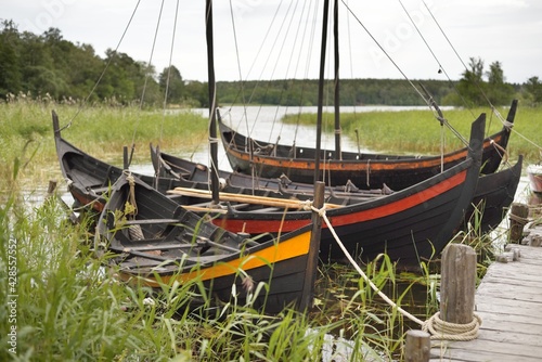 Wooden sailing boats moored to a pier. Birka, Björkö island, lake Mälaren, Sweden. Atmospheric landscape. Travel destinations, landmarks, sightseeing, history, historical reenactment, viking age photo