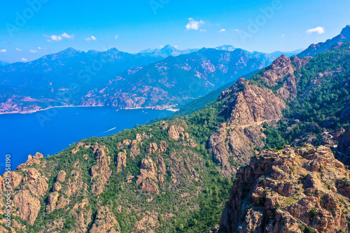 Aerial view of beautiful view of sunlit red mountains and the Mediterranean Sea with the Bay of Porto in Calanches area on Corsica island. Tourism and vacaions concept. Les calanches de Piana, Corsica