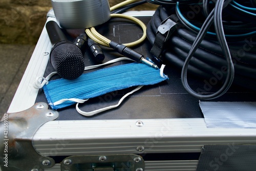 Blue mask laying on a case with some cables (XLR and 1/4" jack), a microphone and a roll of tape, medical mask for protection from all kinds of diseases