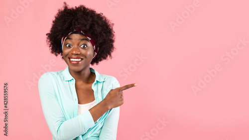 Smiling African American Woman Pointing Finger Aside Over Pink Background
