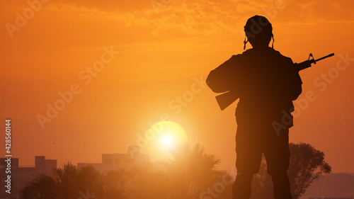 Silhouette Of A Solider Saluting Against coastal town . Concept - protection, patriotism, honor.