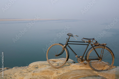 Early morning landscape view of river Ganges with ancient traditional black bicycle in foreground, Rajshahi, Bangladesh