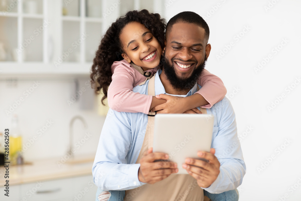 Obraz premium Happy African American family using tablet in the kitchen