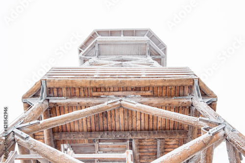 A snow-covered wooden lookout tower on top of the Czernica Mountain. Winter landscape in the Sudetes on a hiking trail.