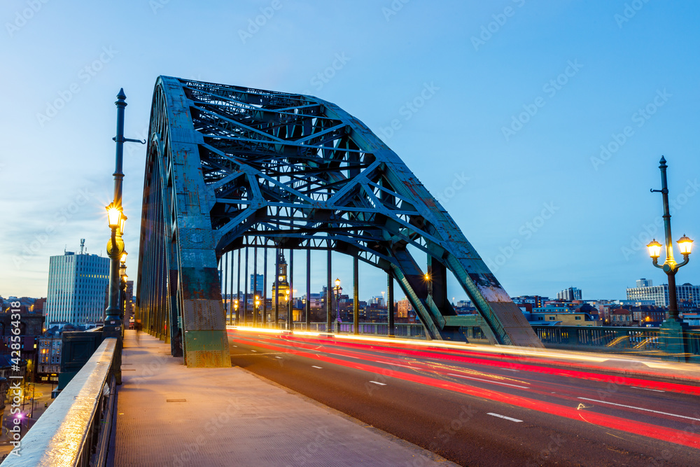 Obraz premium Newcastle upon Tyne UK: 16th March 2021: Tyne Bridge long exposure with blurred traffic during rush hour and blue hour