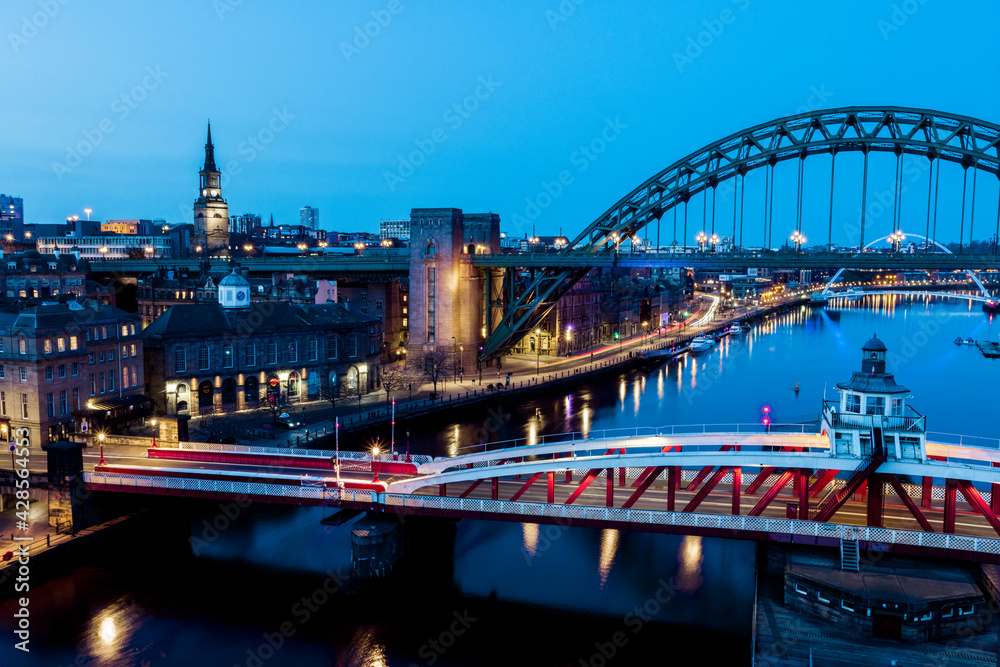 Obraz premium Newcastle upon Tyne UK: 30th March 2021: Newcastle Gateshead Quayside at night, with of Tyne Bridge and city skyline, long exposure during blue hour