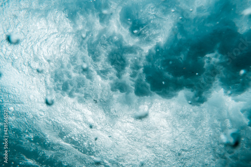 Underwater View of Wave Crashing to Shore Spraying Drops of Water Across the Sea