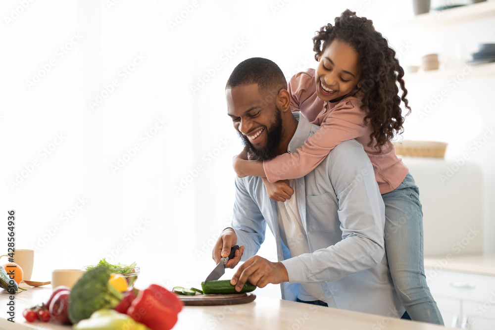 African american father and daughter cooking salad