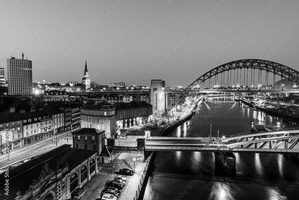 Obraz premium Newcastle upon Tyne UK: 30th March 2021: Newcastle Gateshead Quayside at night, with of Tyne Bridge and city skyline, long exposure in monochrome