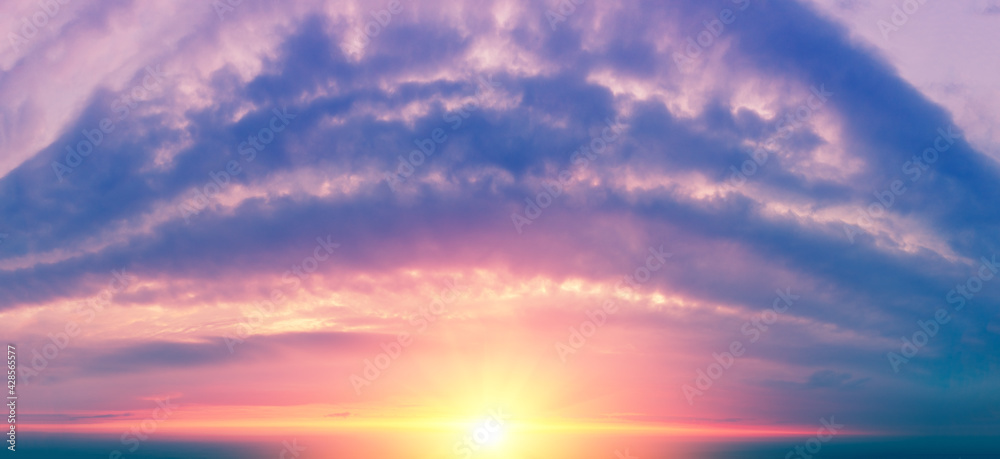 Fantastic panorama of the dramatic cloudy blazing sky in the evening. Clouds in shape arch. Colorful cloudy sky at sunset. Gradient color. Sky texture. Abstract nature background