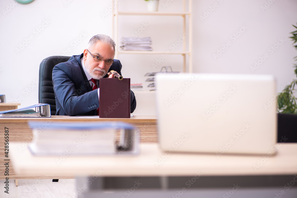 Old businessman employee holding riffle in the office