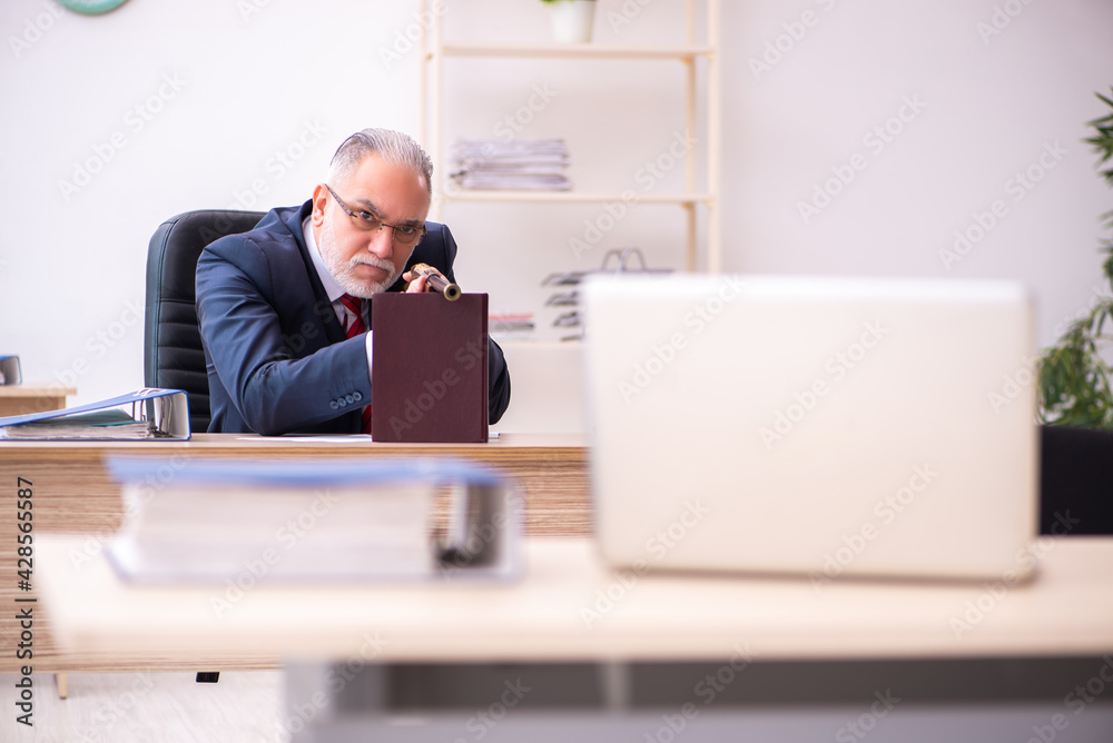Old businessman employee holding riffle in the office Old businessman employee holding riffle in the office