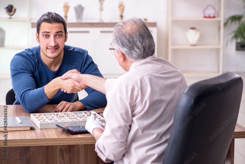 Obraz premium Young man visiting old male jeweler
