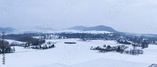 Winter landscape on a cloudy evening with a view of Krosnowice. © Castigatio