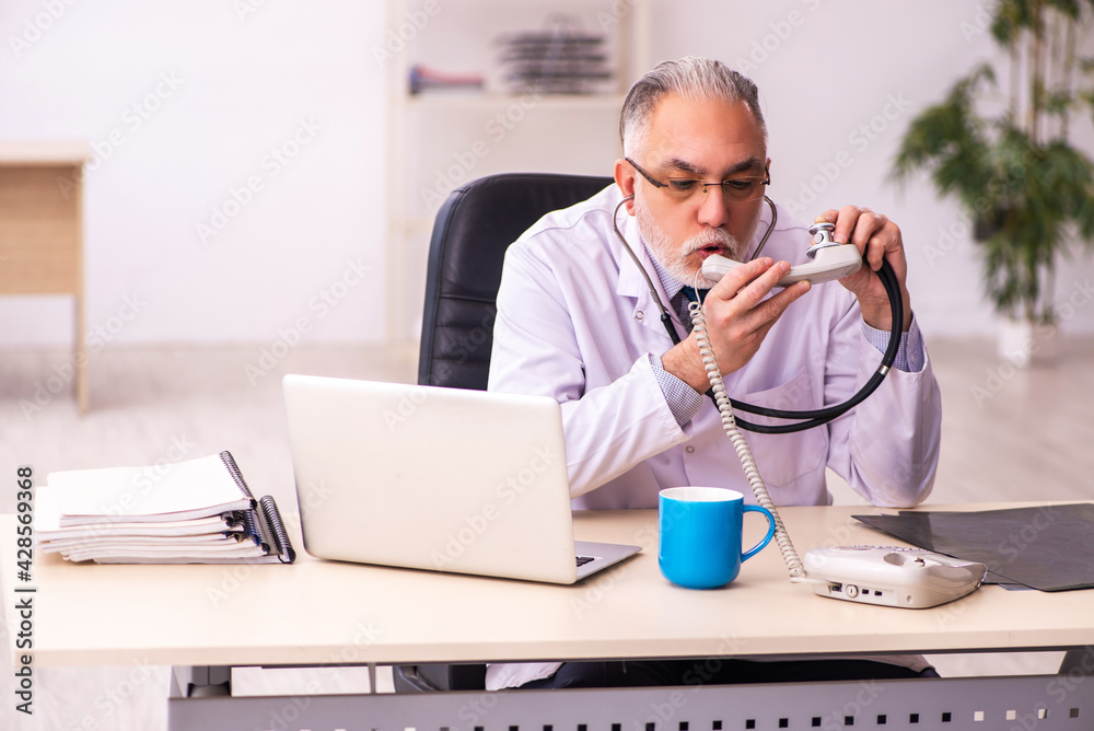 Aged male doctor working in the clinic Aged male doctor working in the clinic