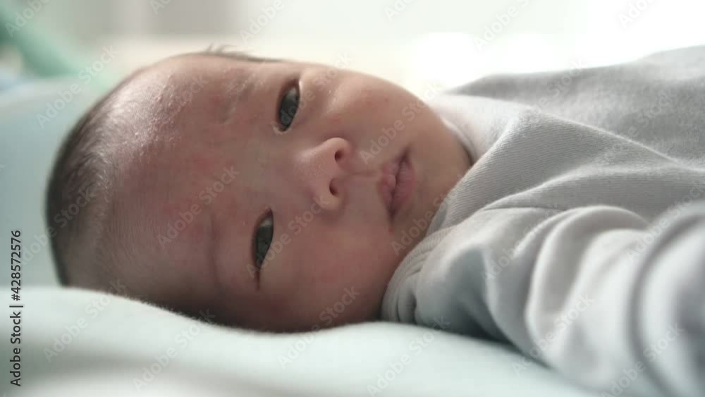 Asian Adorable little newborn baby lying on bed having hiccups. Asian Adorable little newborn baby lying on bed having hiccups.