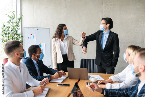 Businessman And Businesswoman Bumping Elbows Wearing Face Masks In Office