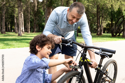 Closeup portrait of cheerful dad and son fixing bike