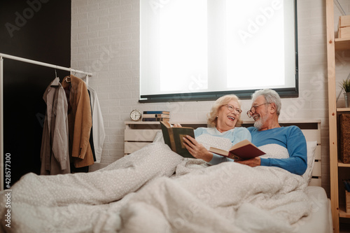 Senior couple happy smile on their bed at home while reading books.