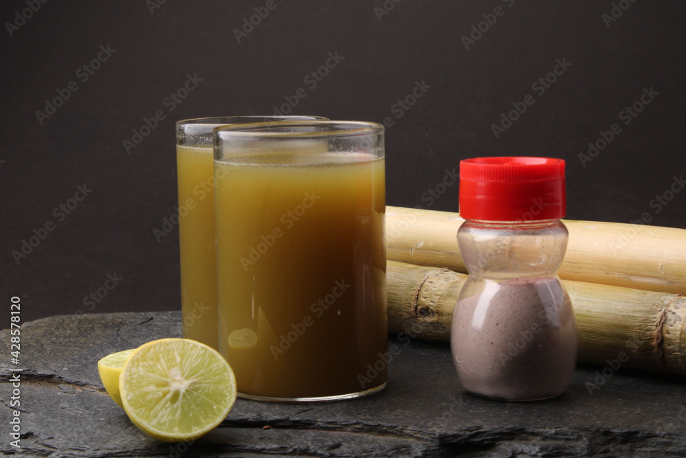 Sugarcane juice in glass with piece of sugarcane, lemon and black salt Sugarcane juice in glass with piece of sugarcane, lemon and black salt