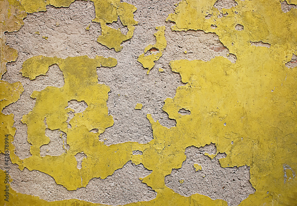 Texture of old yellow plaster wall. Distressed gray concrete wall with dirty yellow paint. Grunge yellow stucco wall background.