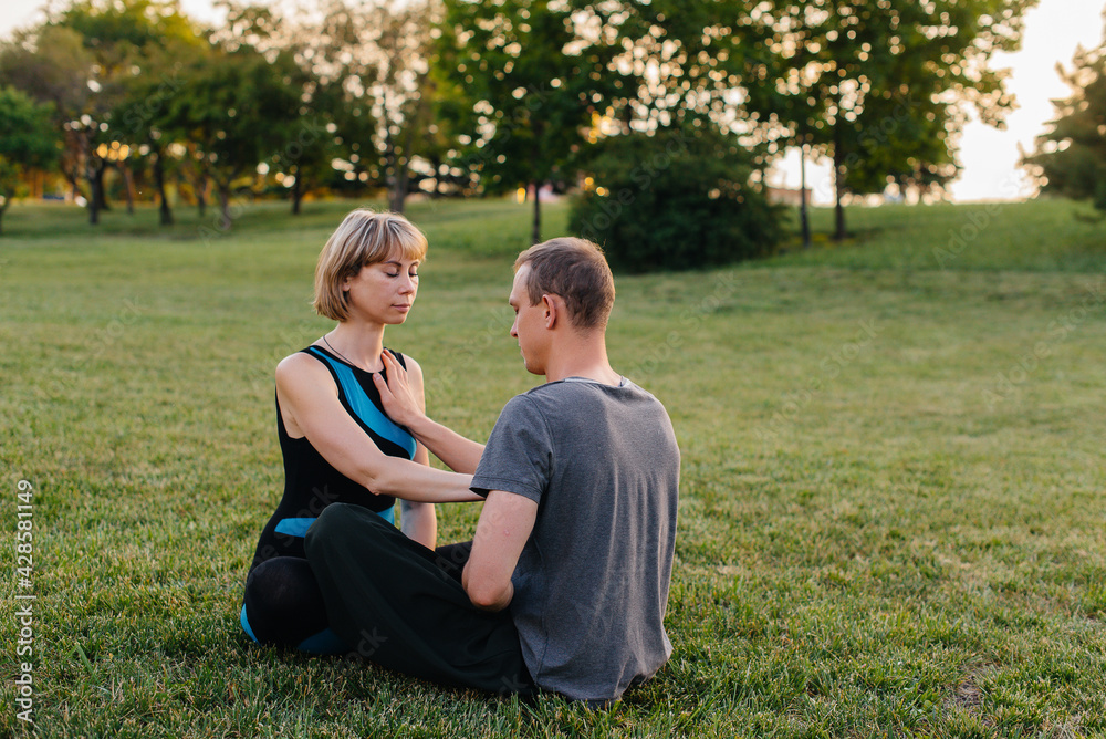 A group of people perform paired yoga exercises in a Park during sunset. Healthy lifestyle, meditation and Wellness A group of people perform paired yoga exercises in a Park during sunset. Healthy lifestyle, meditation and Wellness