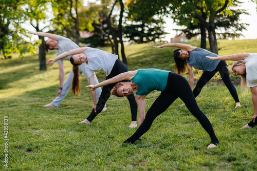 A group of people do yoga in the Park at sunset. Healthy lifestyle, meditation and Wellness