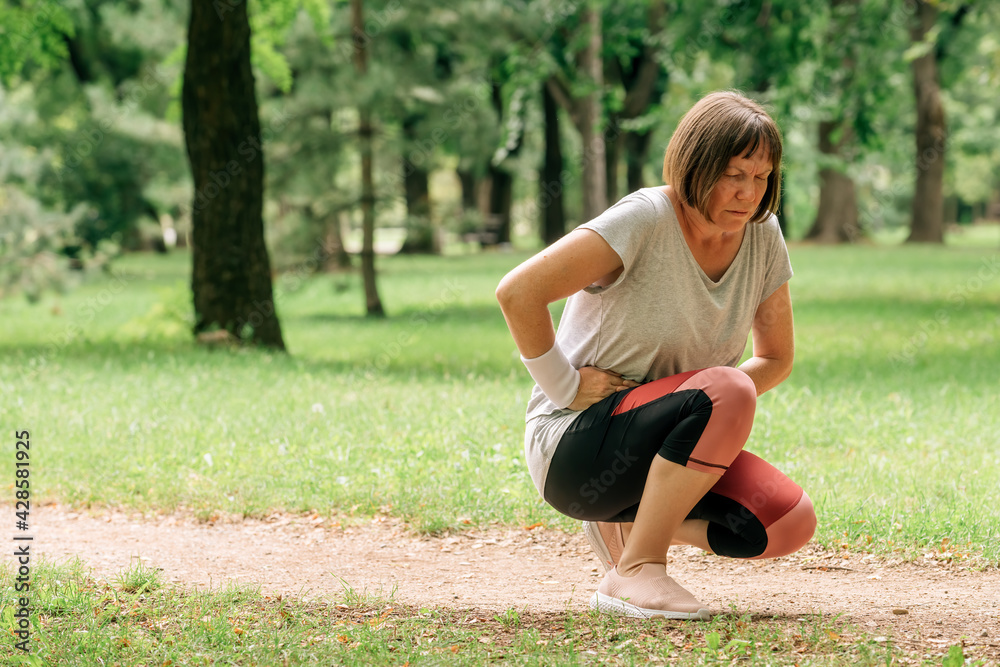 Female jogger with painful face grimace after feeling pain in lower abdomen Female jogger with painful face grimace after feeling pain in lower abdomen