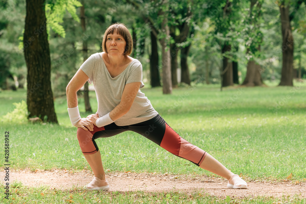 Female jogger stretching muscles and warming up for running exercise in park Female jogger stretching muscles and warming up for running exercise in park