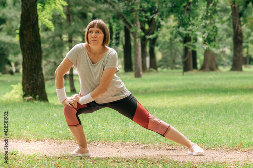 Female jogger stretching muscles and warming up for running exercise in park