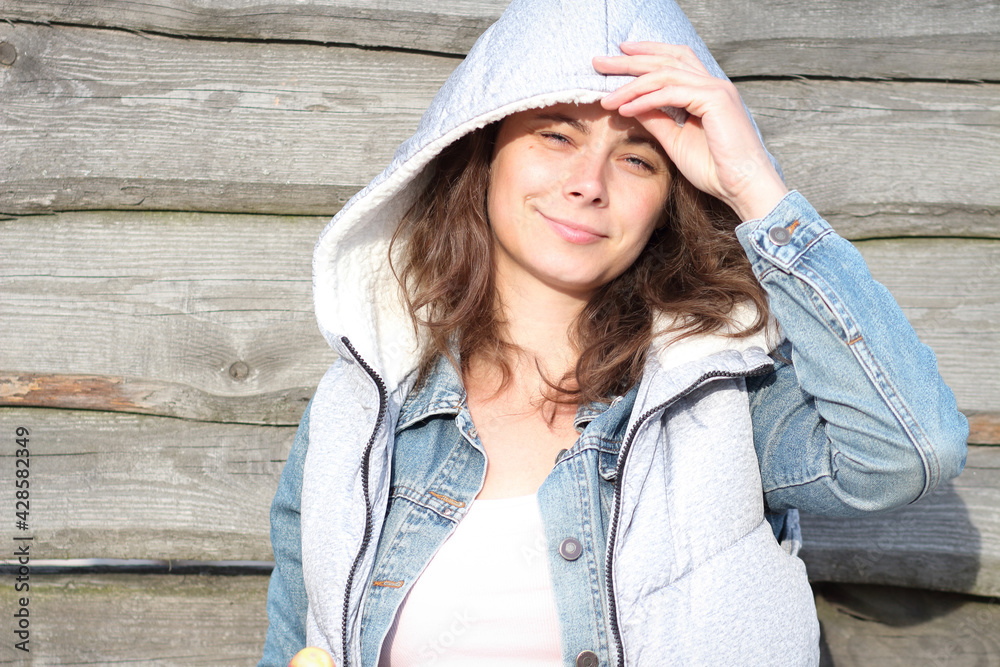 Pretty girl student posing near wooden background. Summer mood. Portrait of caucasian girl against a natural wooden fence.