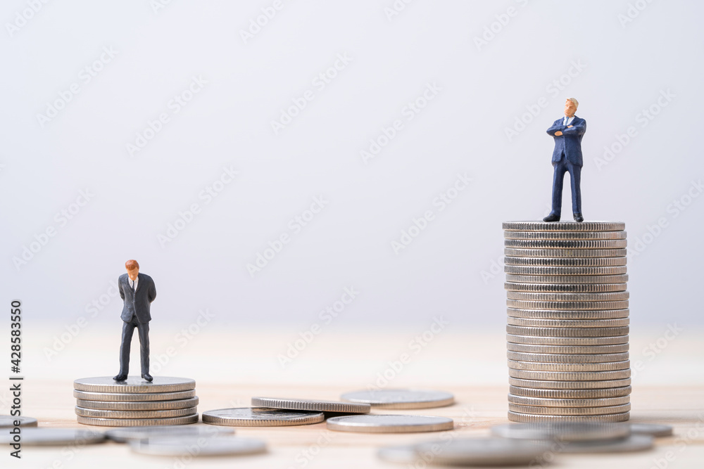 Miniature rich man and poor man standing standing on different height coins stacking , Inequality income and salary concept. Miniature rich man and poor man standing standing on different height coins stacking , Inequality income and salary concept.