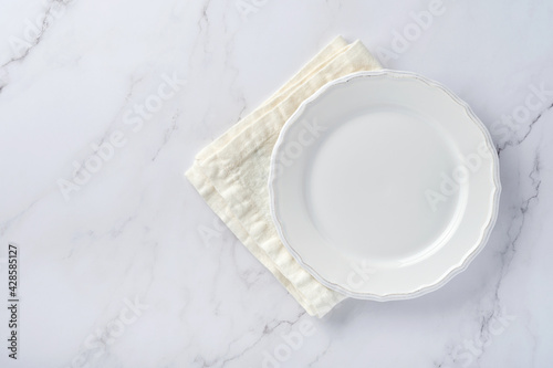 Empty white plate and towel over white marble table for your recipe or menu. Top view. Mock up.