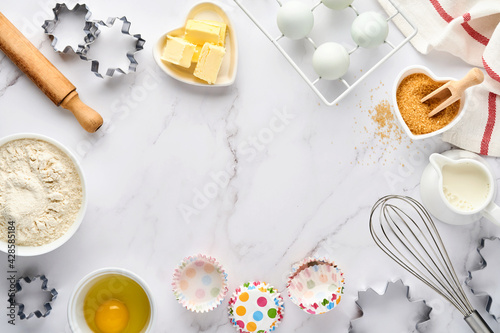 Baking background with flour, eggs, kitchen tools, utensils and cookie molds on white marble table. Top view. Flat lay style. Mock up.