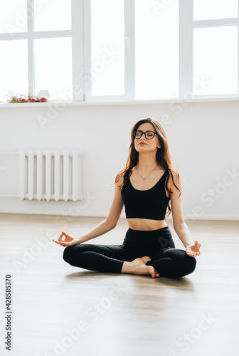 Beautiful brunette fitness woman meditate, doing yoga indoors at home. Staying fit and healthy