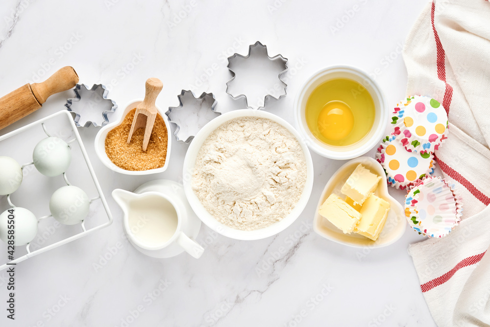 Baking background with flour, eggs, kitchen tools, utensils and cookie molds on white marble table. Top view. Flat lay style. Mock up.